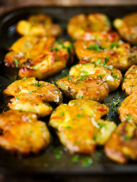 Crispy roasted crushed (smashed) new potatoes garnished with parsley.