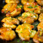 Crispy roasted crushed (smashed) new potatoes garnished with parsley.