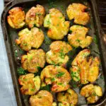Overhead crispy roasted crushed (smashed) new potatoes on a roasting tray.