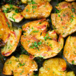 Overhead close-up crispy roasted crushed (smashed) new potatoes on a roasting tray.