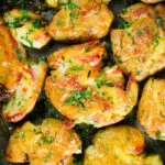 Overhead close-up crispy roasted crushed (smashed) new potatoes on a roasting tray.