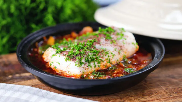 Cod fish tagine with preserved lemons garnished with sumac and parsley.