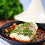 Cod fish tagine with preserved lemons, harissa and sumac in a traditional pot.