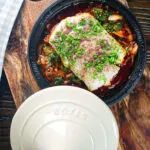 Overhead cod fish tagine with preserved lemons, harissa and sumac in a traditional pot.