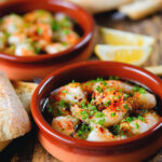Spanish gambas (prawns) pil pil served with fresh parsley, bread and lemon wedges.