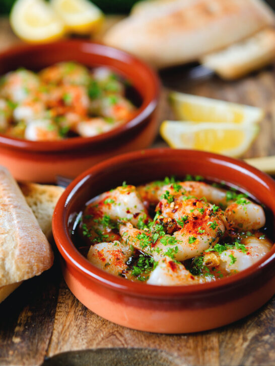 Spanish gambas (prawns) pil pil served with fresh parsley, bread and lemon wedges.