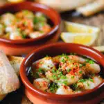Spanish gambas (prawns) pil pil served with fresh parsley, bread and lemon wedges.