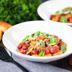 Potato gnocchi with a rich red wine and tomato sauce garnished with basil and Parmesan cheese.