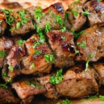 Close-up lamb souvlaki skewers served with Greek flatbreads.
