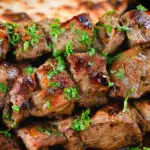 Close-up lamb souvlaki skewers served with Greek flatbreads.
