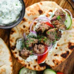 Lamb souvlaki served with tzatziki, salad on Greek flatbreads.