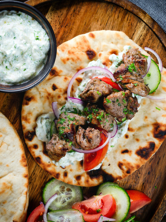 Lamb souvlaki served with tzatziki, salad on Greek flatbreads.