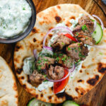 Lamb souvlaki served with tzatziki, salad on Greek flatbreads.