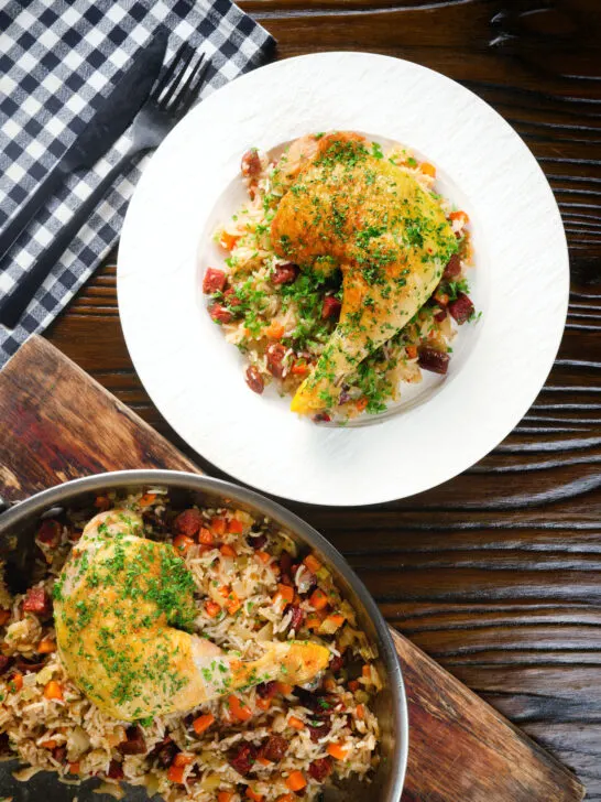 Overhead Spanish-influenced baked chicken and chorizo rice served on a plate.
