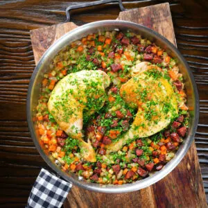 One-pot baked chicken leg and chorizo rice garnished with fresh parsley.