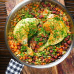 Overhead Spanish-influenced baked chicken and chorizo rice in a cooking pan.
