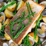 Overhead close-up pan fried sea trout fillets with clams, new potatoes and fresh samphire.