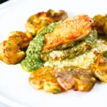 Baked pesto and mozzarella stuffed chicken breast with crushed roasted new potatoes.