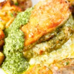 Close-up baked pesto and mozzarella stuffed chicken breast with crispy crushed potatoes.