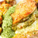Close-up baked pesto and mozzarella stuffed chicken breast with crispy crushed potatoes.