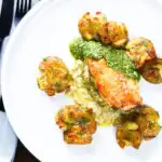Overhead pesto and mozzarella stuffed chicken breast with crushed roasted new potatoes.