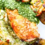 Overhead close-up baked pesto and mozzarella stuffed chicken breast with crispy crushed potatoes.
