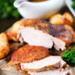 Carved slow cooker pork loin, cider gravy, roast potatoes and green vegetables.