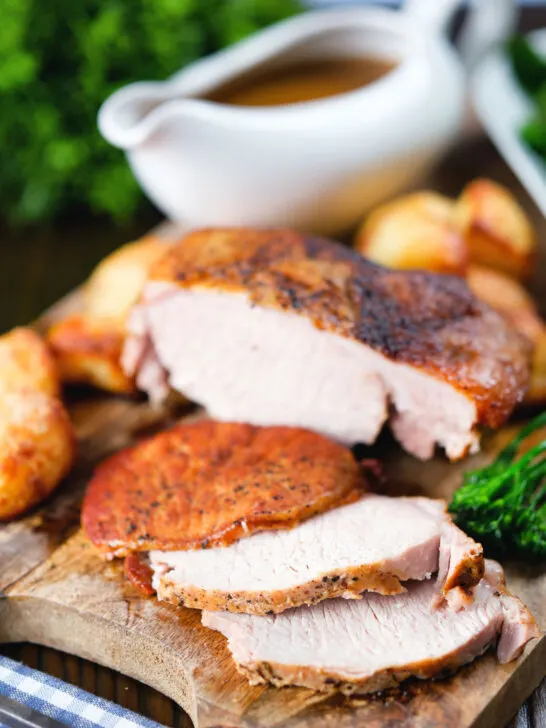 Carved slow cooker pork loin, cider gravy, roast potatoes and green vegetables.