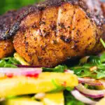 Close-up pan-fried Cajun Blackened cod fish served with mango salad.