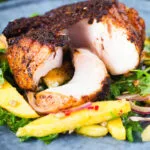 Cajun Blackened cod cut open showing white flaked fish served with mango salad.
