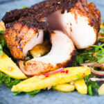 Cajun Blackened cod cut open showing white flaked fish served with mango salad.