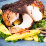 Cajun Blackened cod cut open showing white flaked fish served with mango salad.