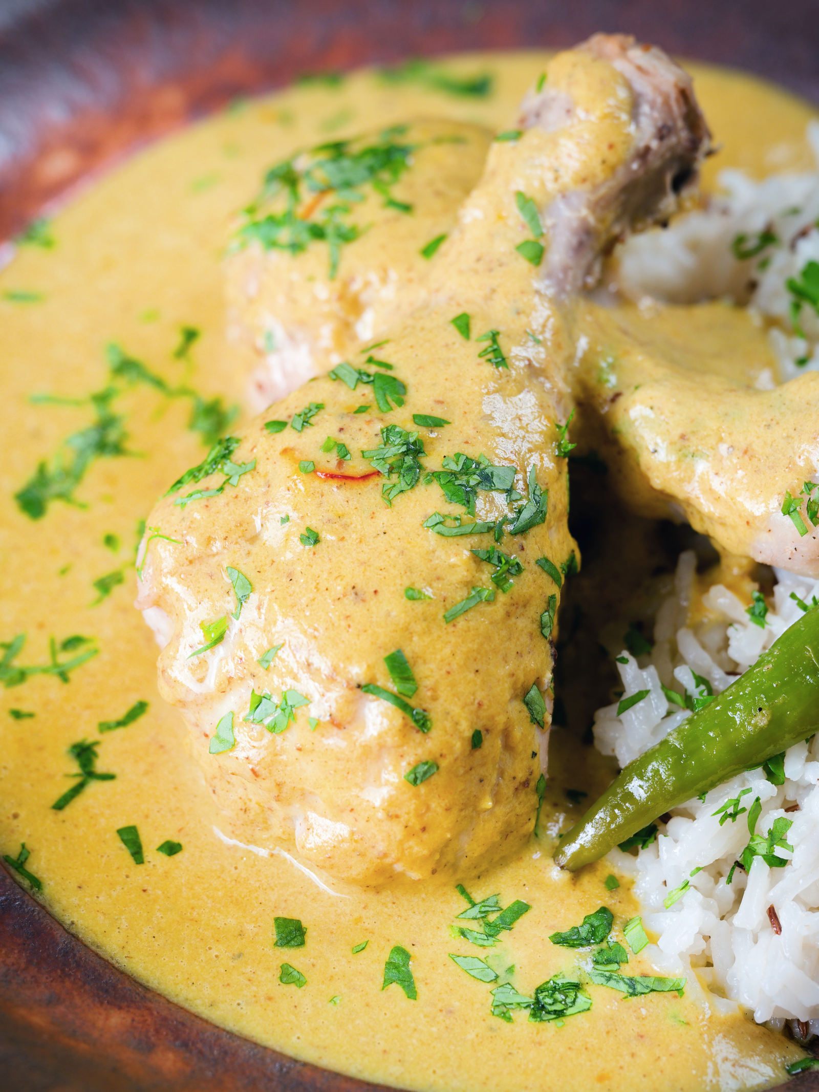 Close-up chicken drumstick rezala curry serve with jeera (cumin) rice.