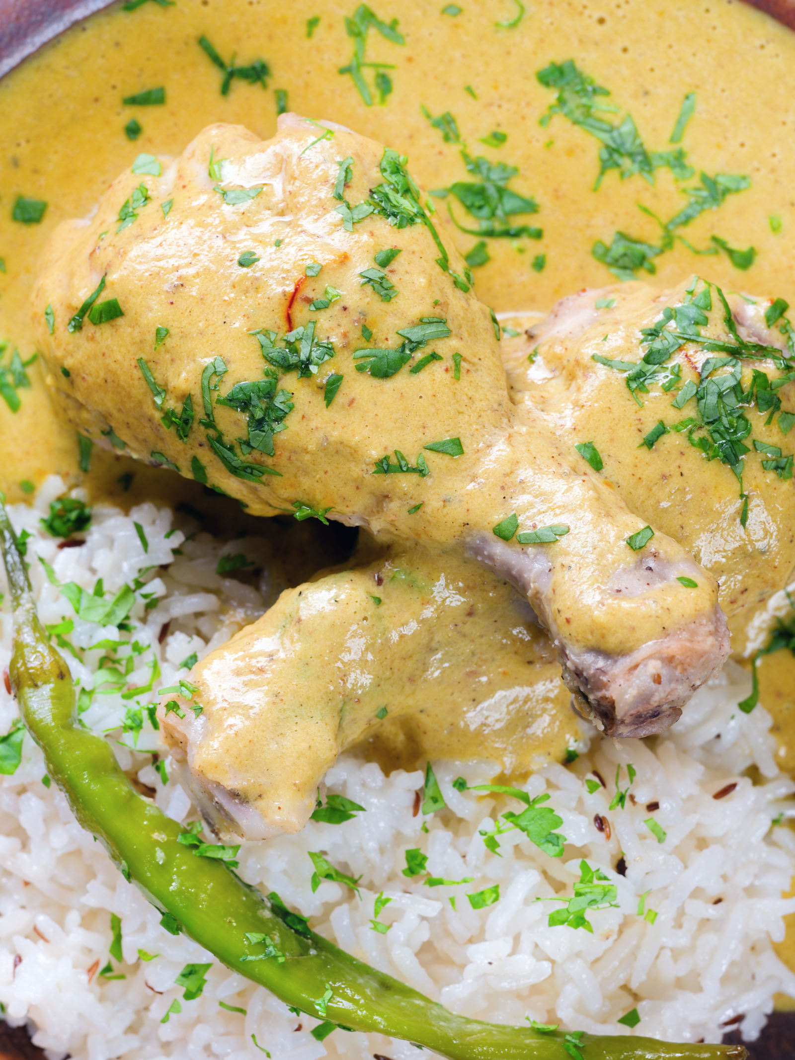 Overhead close-up chicken drumstick rezala curry serve with jeera (cumin) rice.