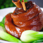 Chinese braised pork knuckle or shank served with steamed pak choi.