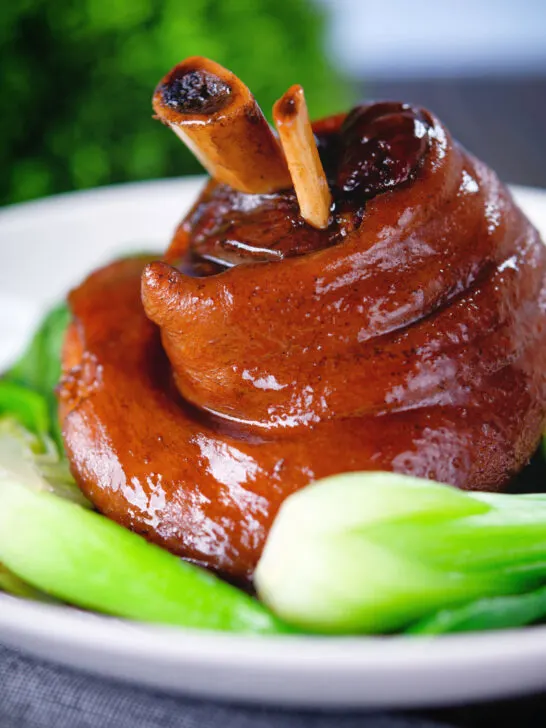 Chinese braised pork knuckle or shank served with steamed pak choi.