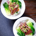 Overhead shredded braised Chinese pork knuckle with rice and steamed pak choi.