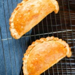 Overhead homemade corned beef, onion and potato pasties made with shortcrust pastry.