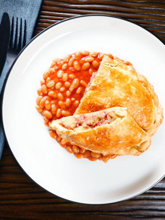 Overhead homemade corned beef, onion and potato pasty served with baked beans.