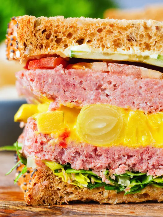 Close-up canned corned beef sandwich with piccalilli on wholegrain seeded bread.