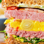 Close-up canned corned beef sandwich with piccalilli on wholegrain seeded bread.