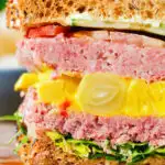 Close-up canned corned beef sandwich with piccalilli on wholegrain seeded bread.