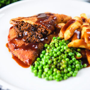 Minced beef stuffed homemade crispy pancakes with chips, peas and gravy.