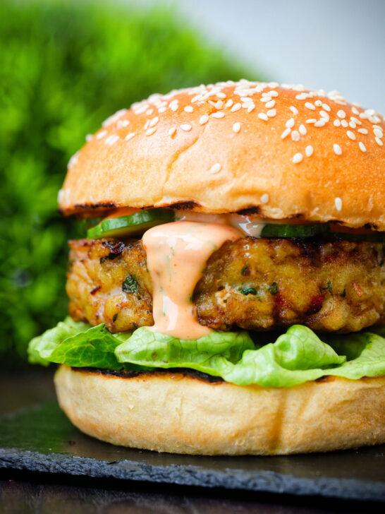 Close up fish burger with Thai flavours topped with sriracha mayonnaise and cucumber.