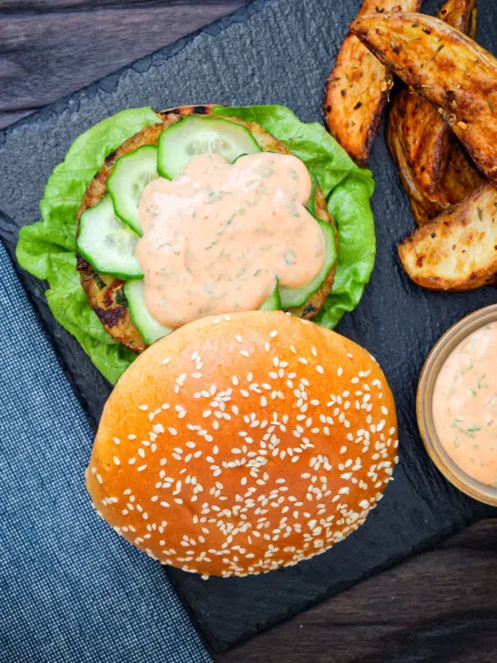 Overhead fish burger with Thai flavours topped with sriracha mayonnaise and cucumber.