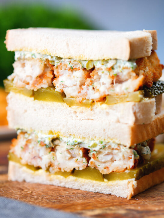 Close up fish finger sandwich with homemade tartar sauce and gherkins.