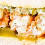 Detail shot of a fish finger sandwich with homemade tartar sauce and gherkins.