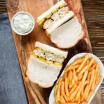 Overhead fish finger sandwich with homemade tartar sauce served with French fries.