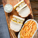 Overhead fish finger sandwich with homemade tartar sauce served with French fries.