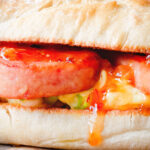 Close-up Spam, scrambled egg and spring onion sandwich with sweet chilli sauce.
